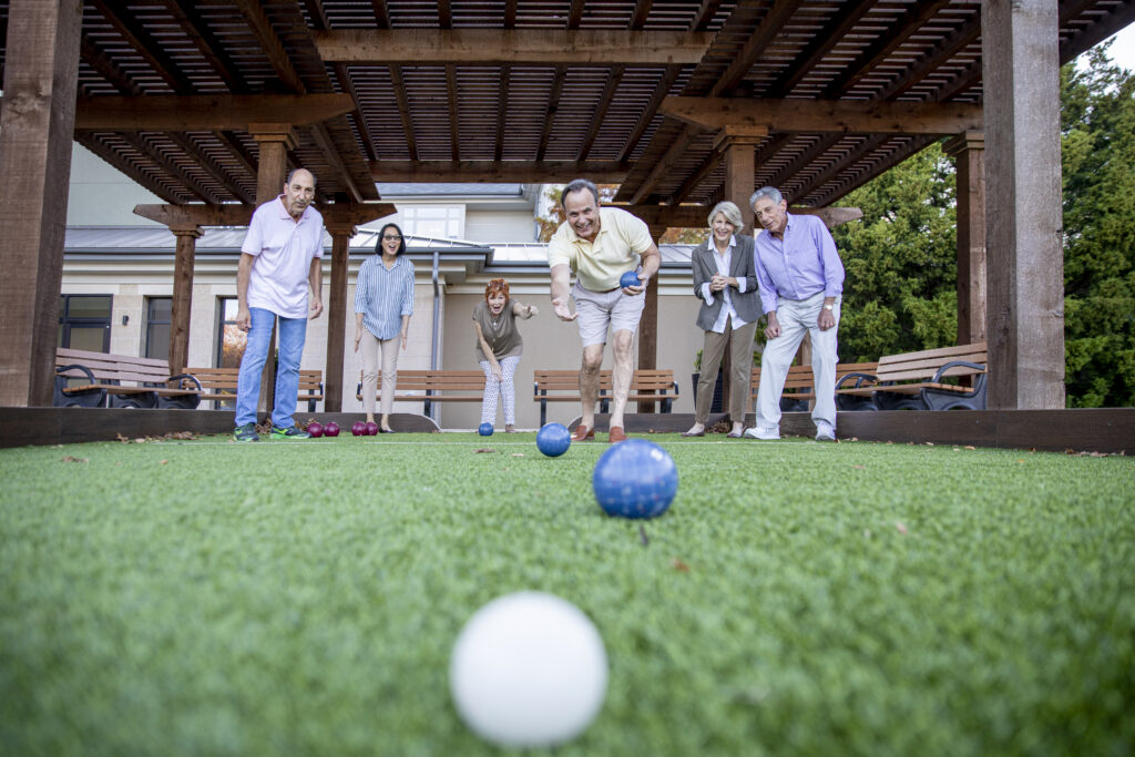 A group of older adults plays bocce ball at a senior community
