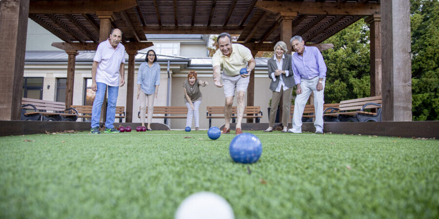 A group of older adults plays bocce ball at a senior community