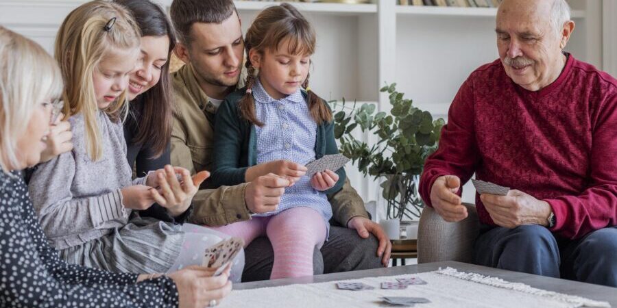 An older couple playing cards with their grandchildren