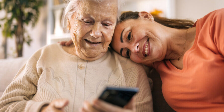 Senior mother and daughter using smartphone at home.