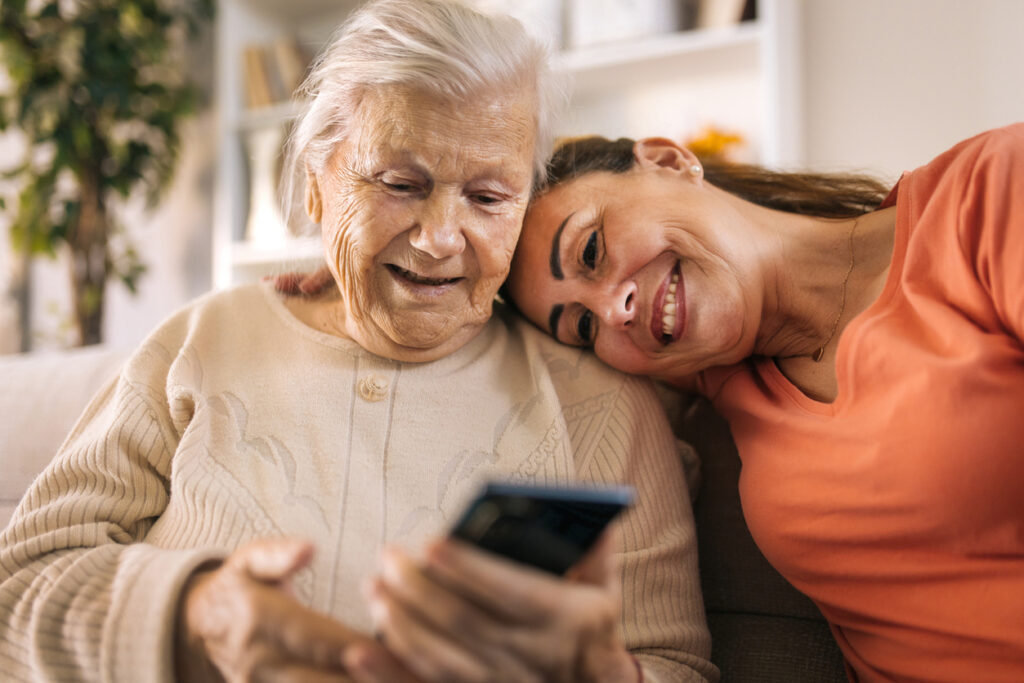 Senior mother and daughter using smartphone at home.