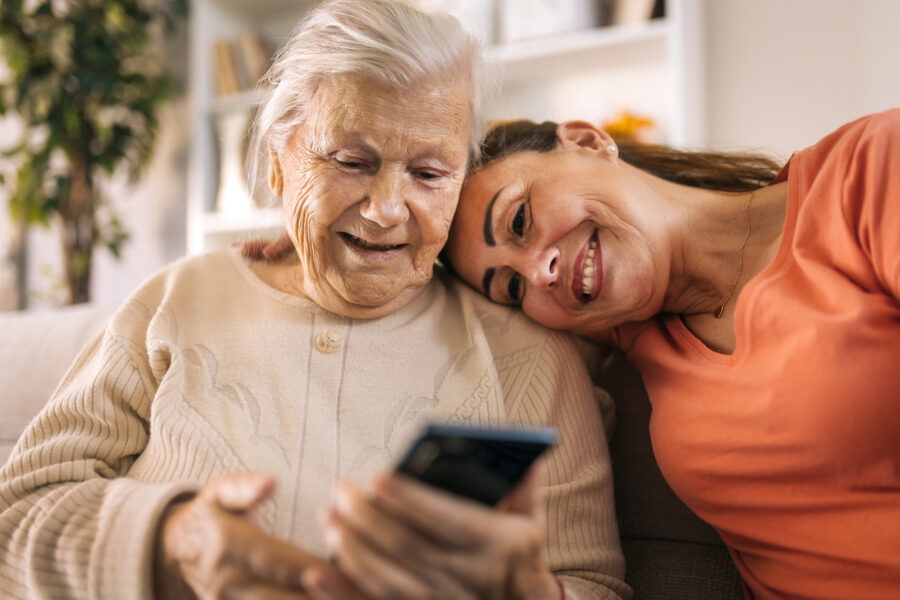 Senior mother and daughter using smartphone at home.