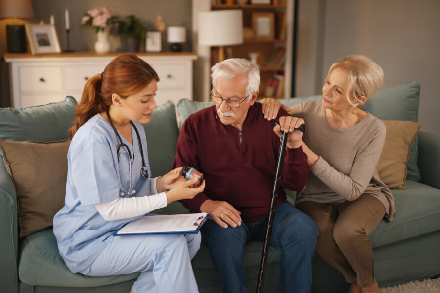 Nurse explaining medicine to senior couple at home